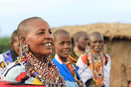 Maasai people in traditional clothing gather in the grasslands.