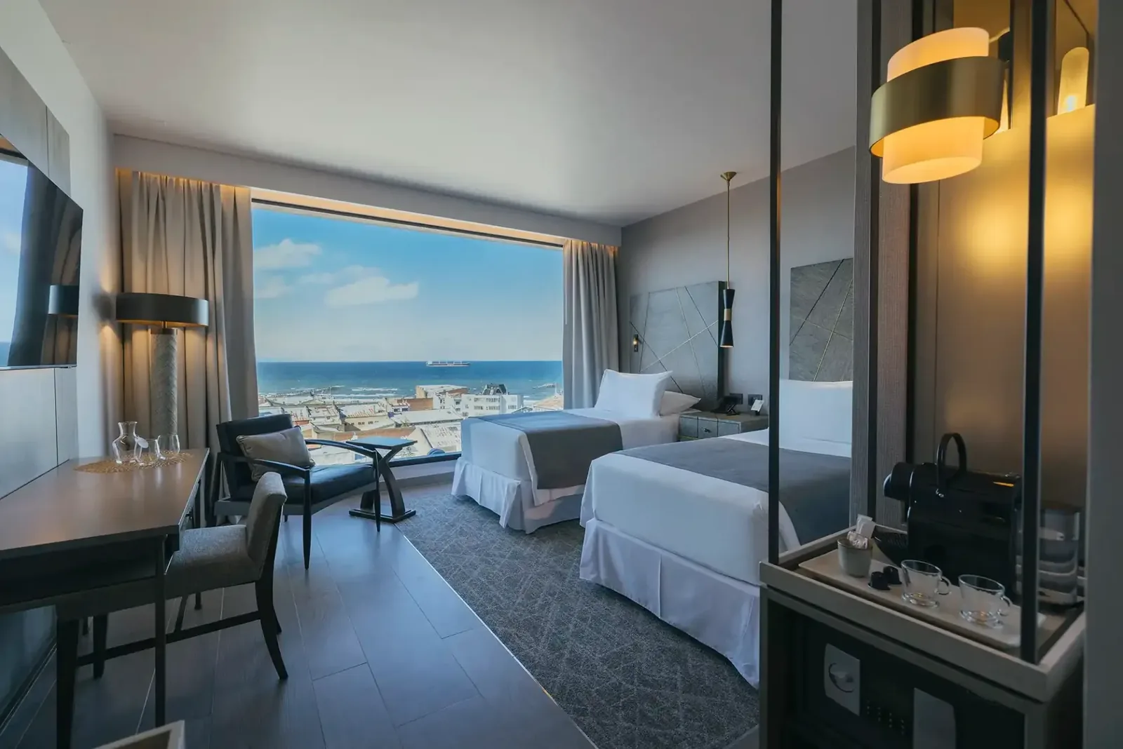 A hotel room opens toward a broad view of the sea.