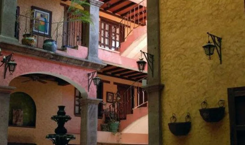 A shaded courtyard with pink stucco walls and tropical planting.