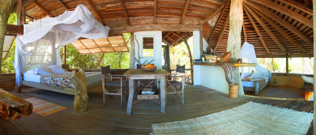 A simple island-lodge bedroom with a timber roof and mosquito-netted bed.