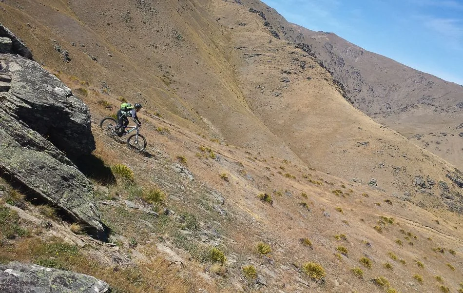 A mountain biker rides a remote rocky trail in New Zealand's high country.
