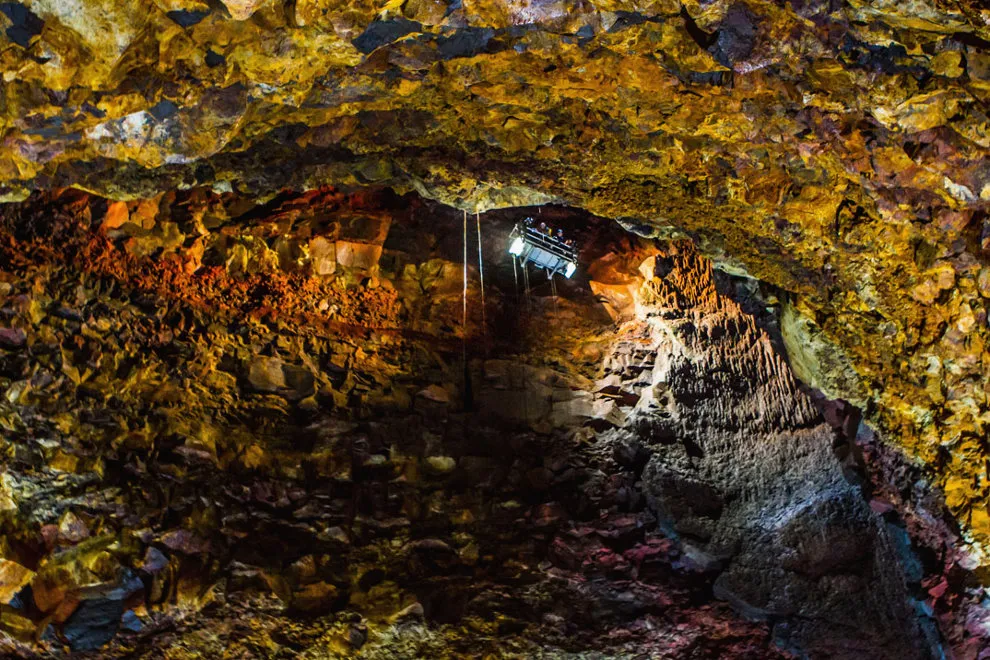 An underground volcanic chamber with rough, vividly lit rock walls.