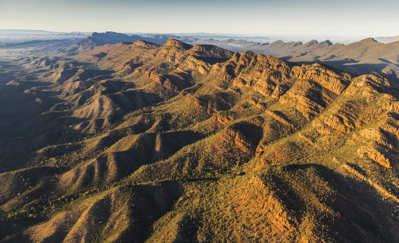 Aerial view of rugged sunlit ridges in the Flinders Ranges.