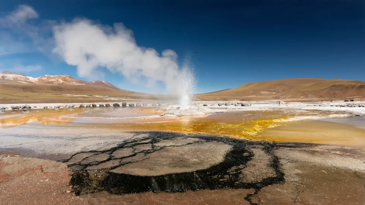 Steam rising from a geyser in a high-altitude desert landscape.