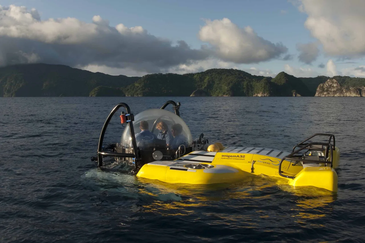 A yellow submersible with a transparent passenger canopy on the water.