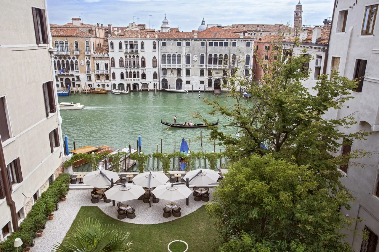 A garden terrace overlooking Venice's Grand Canal and buildings along the opposite bank.