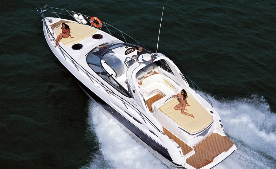 A white motor yacht with pale wood decking floating on dark water.