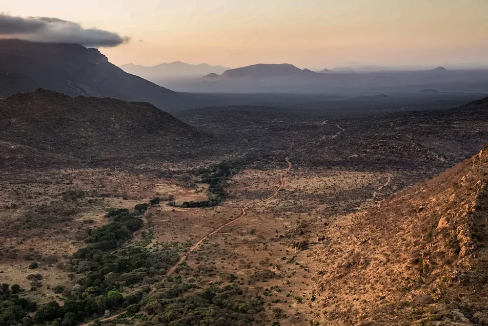 A river winding through a dry valley at sunset.