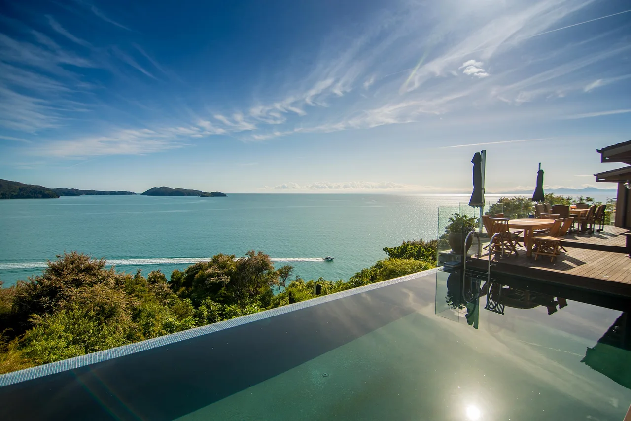 An infinity pool and terrace overlooking a broad coastal bay.